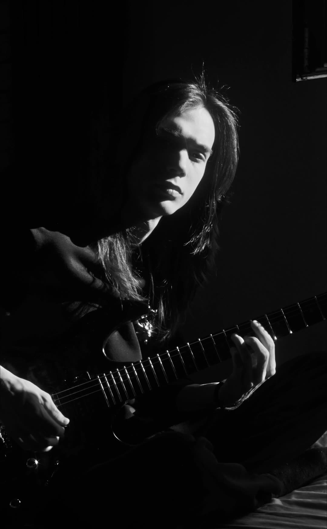 Karanlık odada yandan tek ışıkla aydınlanan eminlead, elinde gitar